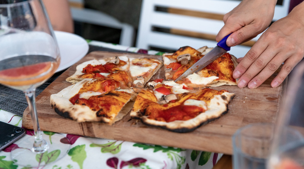 Pizza wird auf einem Holzbrett geschnitten